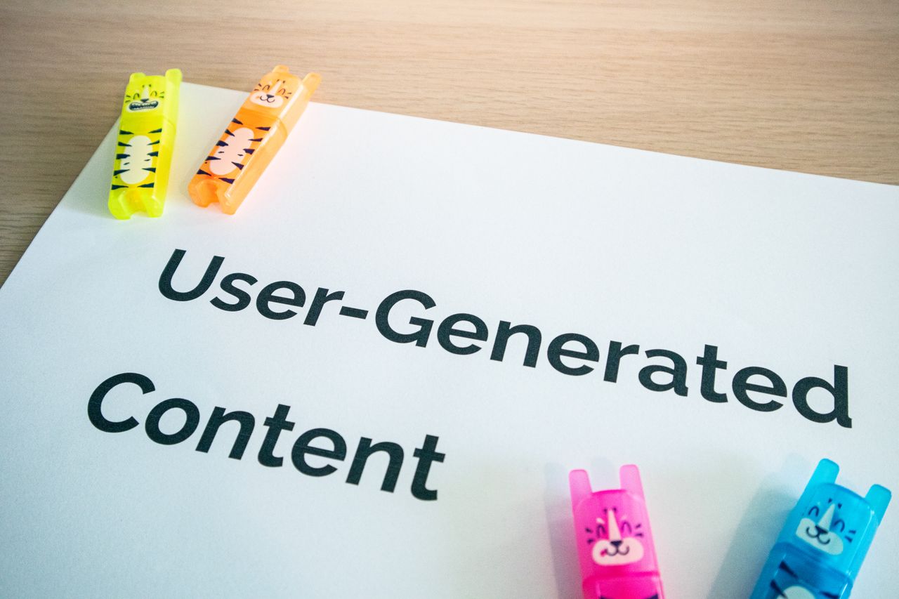 Des surligneurs vifs posés sur une note de User-Generated Content, sur fond de bureau en bois.